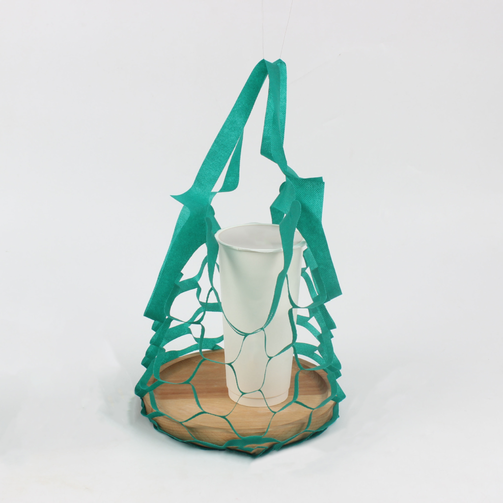 Disposable green nonwoven mesh single-cup coffee carrier bag holding a paper coffee cup, with integrated handle