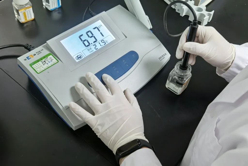 Technician testing pH value of non-woven fabric extract with digital pH meter in Takewind non-woven factory QC laboratory to check fabric acidity and alkalinity