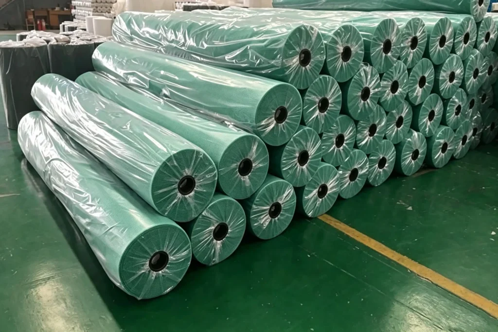 stacked bulk green geotextile rolls packed with plastic film in Takewind factory warehouse