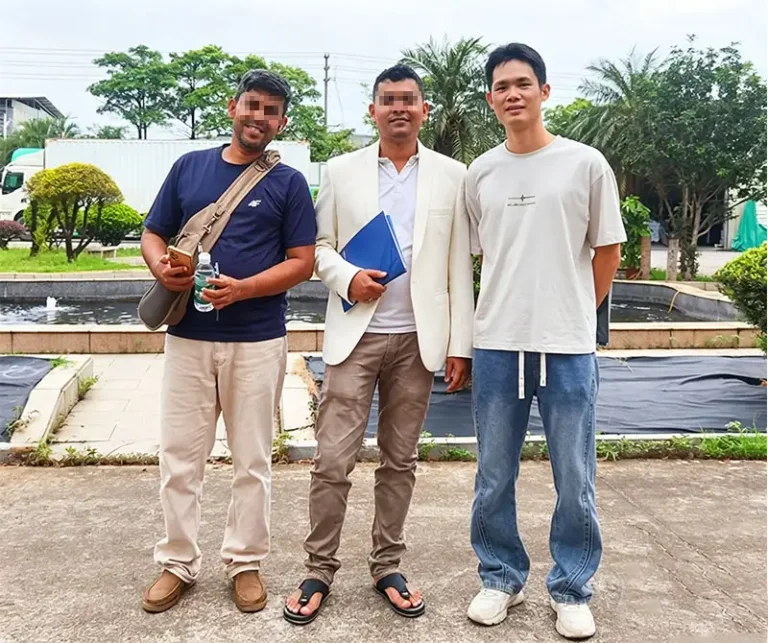 Three men pose for a photo outdoors at Takewind Non-Woven factory; two are automotive filter buyers from Bangladesh, inspecting PP & PET spunbond nonwovens for car air filters.