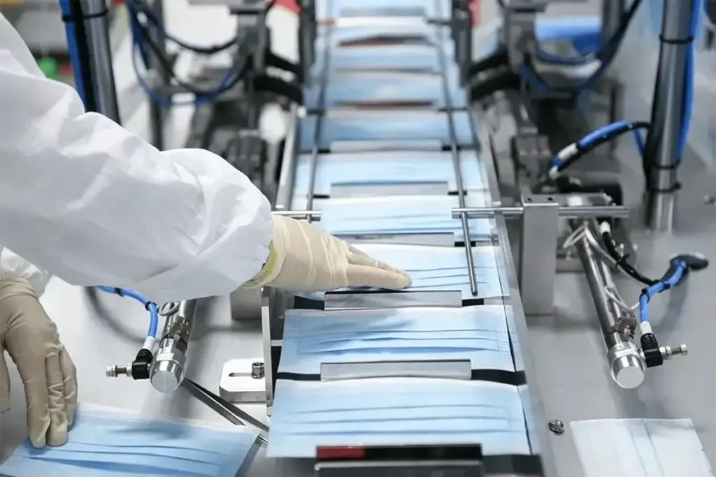 Worker in white protective clothing operating mask production line, mask nonwoven fabric manufacturing