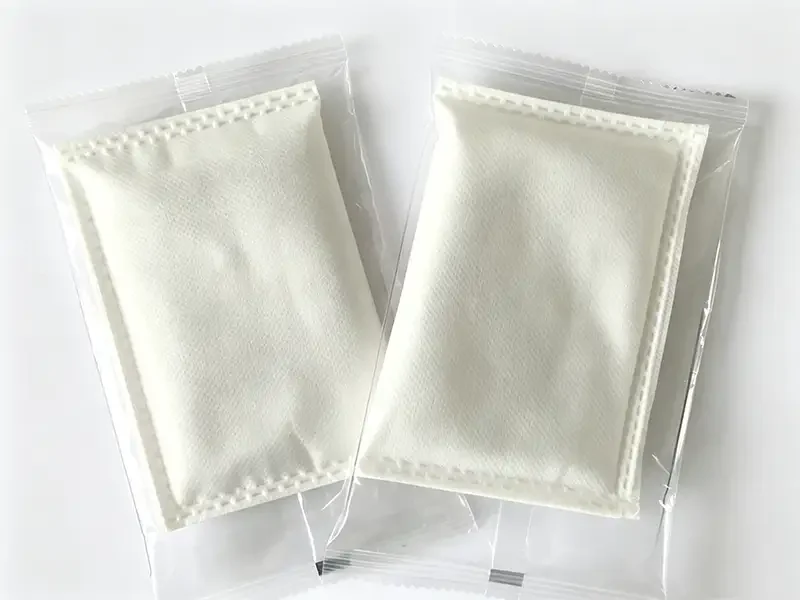 Two sealed white non-woven heating pads packed in transparent plastic bags, stitched edge breathable nonwoven fabric for warm patch outer packaging, Takewind functional nonwoven material