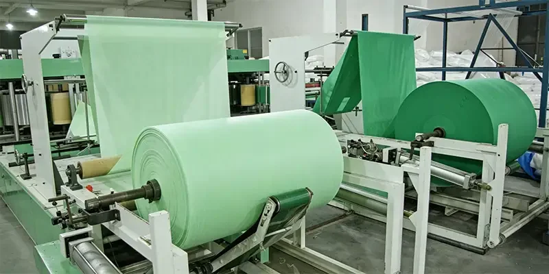 Takewind factory workshop, production machine for disposable hotel nonwoven pillowcase, bed cover, duvet cover, compressed towel and shower cap, large green nonwoven fabric roll on industrial equipment