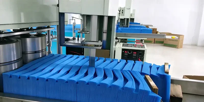 Takewind factory workshop, industrial cutting machine processing stacked blue nonwoven fabric for disposable cleaning cloth